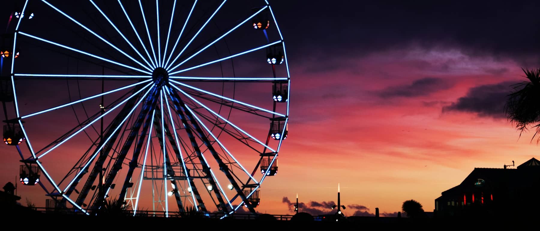 Fairground ferris wheel lit against an evening sky