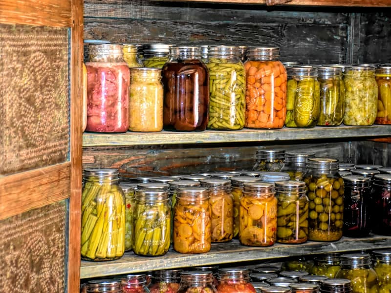 A shelf of home preserves in glass jars